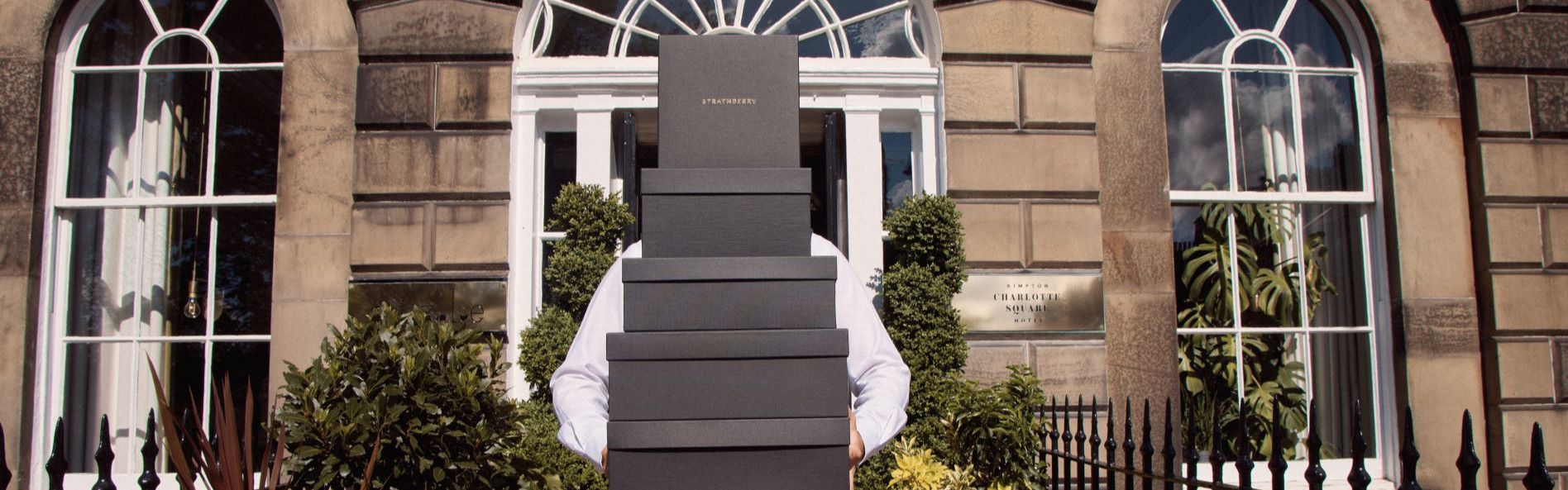 Employee holding boxes of Strathberry outside Kimpton Edinburgh hotel entrance